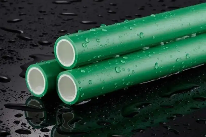 Green plastic pipes on a dark wet surface