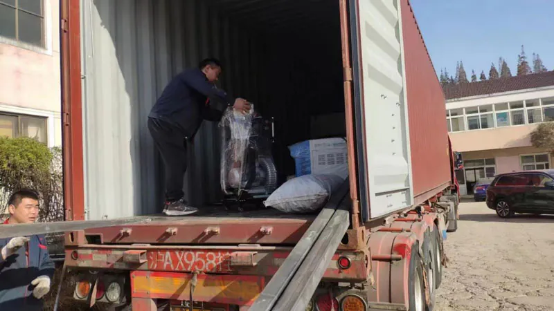 Worker loading machinery into an open shipping container